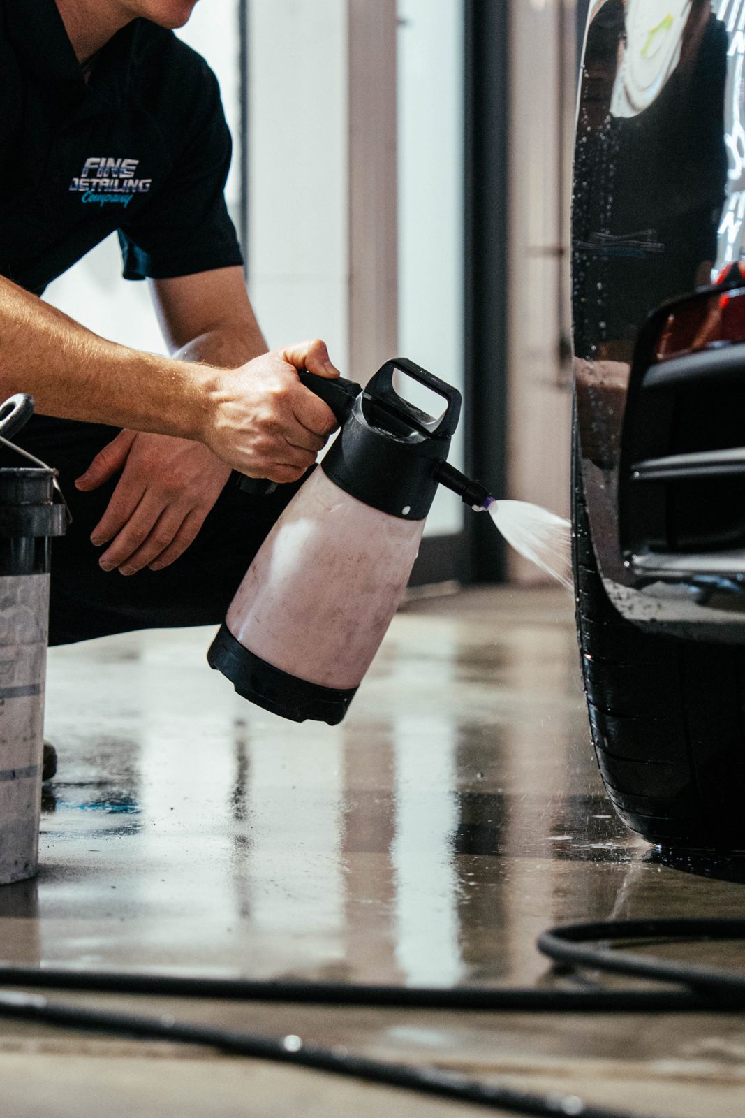 Detailer spraying a car with a foam bottle